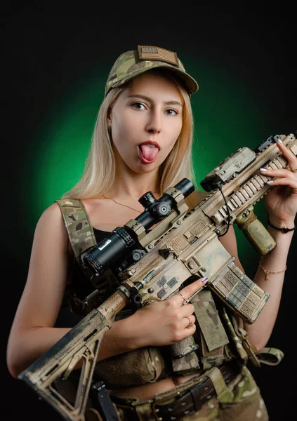Seksowna dziewczyna w wojskowym airsoftowym kombinezonie pozuje z bronią w ręku na ciemnym tle — Zdjęcie stockowe