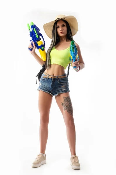 Chica morena con una pistola de agua en la ropa de verano, delgado y sexy — Foto de Stock