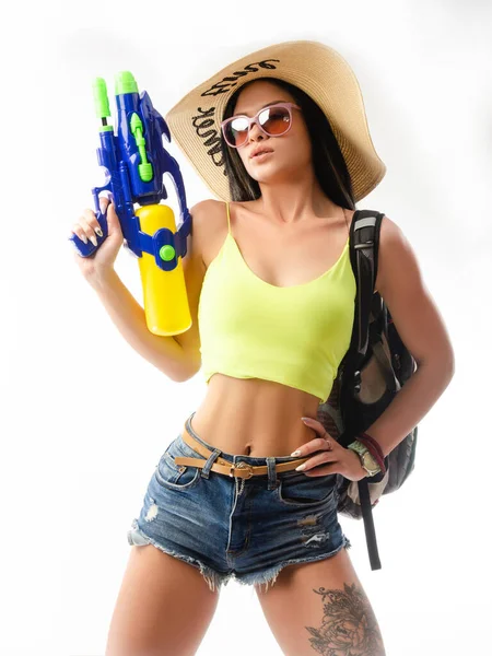 Menina morena com uma pistola de água em roupas de verão, magro e sexy — Fotografia de Stock