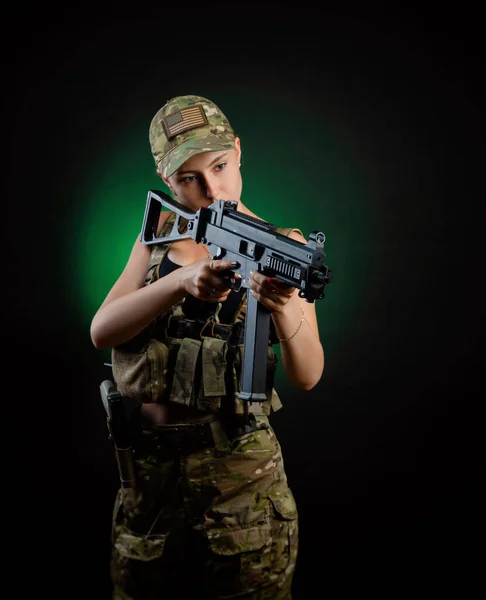 Askeri hava yumuşaklığında seksi bir kız siyah arka planda bir saldırı tüfeğiyle poz veriyor. — Stok fotoğraf