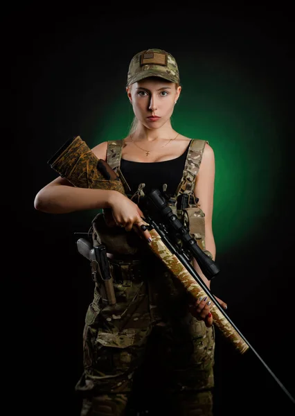 Uma menina sexy no macacão airsoft militar posa com rifle sniper em um fundo escuro — Fotografia de Stock