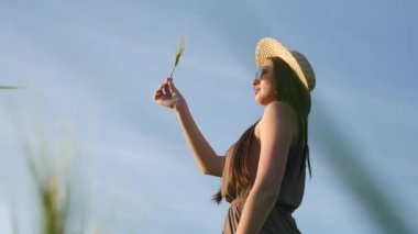 Güzel bir yaz elbisesi ve buğday tarlasında elinde çivi tutan şapkalı bir kız.
