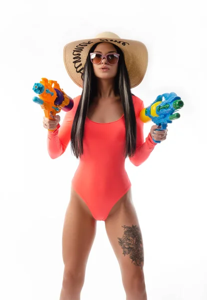 Menina morena com uma pistola de água em roupas de verão, magro e sexy — Fotografia de Stock