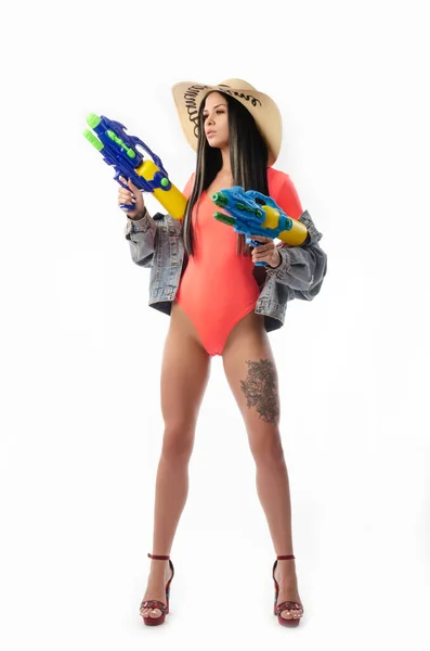 Ragazza bruna con una pistola ad acqua in vestiti estivi, sottile e sexy — Foto Stock