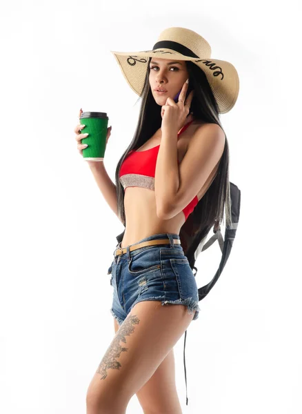 Brunette in a hat in summer clothes slim and sexy with a phone isolated on a white background — Stock Photo, Image