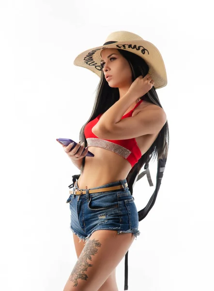 Брюнетка в капелюсі в літньому одязі струнка і сексуальна з телефоном ізольована на білому тлі — стокове фото