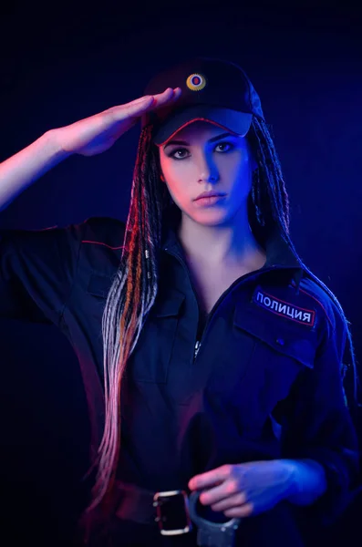 Dívka v policejní uniformě s dredy v neonovém světle s řetězy a pouty Anglický překlad policie — Stock fotografie