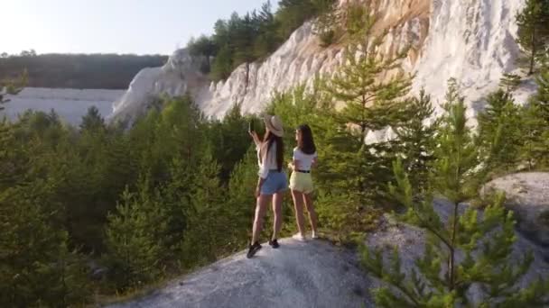 Mädchen in schönen Sommerkleidern und Hüten wandern entlang der Kreideberge — Stockvideo