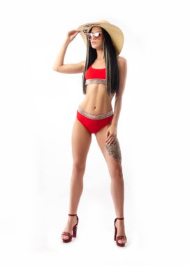 Kırmızı mayo giymiş esmer, ince ve seksi, beyaz arka planda izole edilmiş yaz şapkalı.