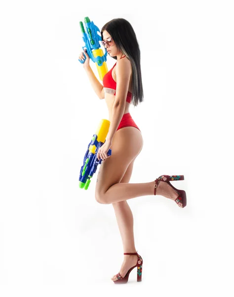 Menina morena com uma arma de água em um maiô vermelho, magro e sexy — Fotografia de Stock