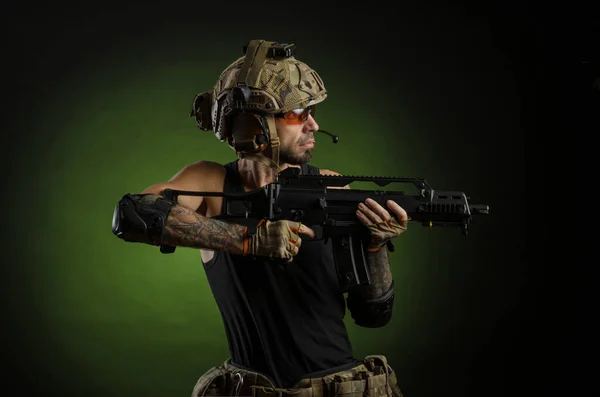 Um homem com uma arma no capacete em um fundo escuro — Fotografia de Stock