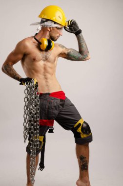 İnşaat tamircisi bir adam elinde metal bir zincir tutuyor.