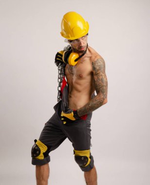 İnşaat tamircisi bir adam elinde metal bir zincir tutuyor.