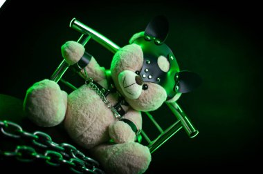 Deri kemer takmış oyuncak ayı. Koyu arkaplanda bdsm oyunları için aksesuar.