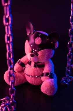 Deri kemer takmış oyuncak ayı BDSM oyunları için aksesuar neon ışıklı karanlık bir arka planda
