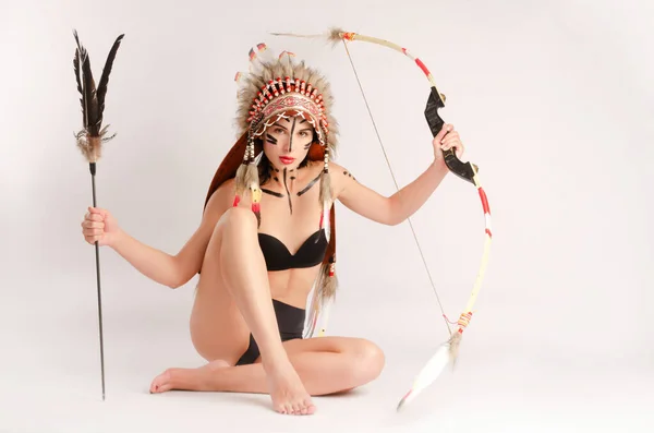 Flicka i bilden av ursprungsbefolkningar i Amerika med en båge och pil poserar på en ljus bakgrund — Stockfoto