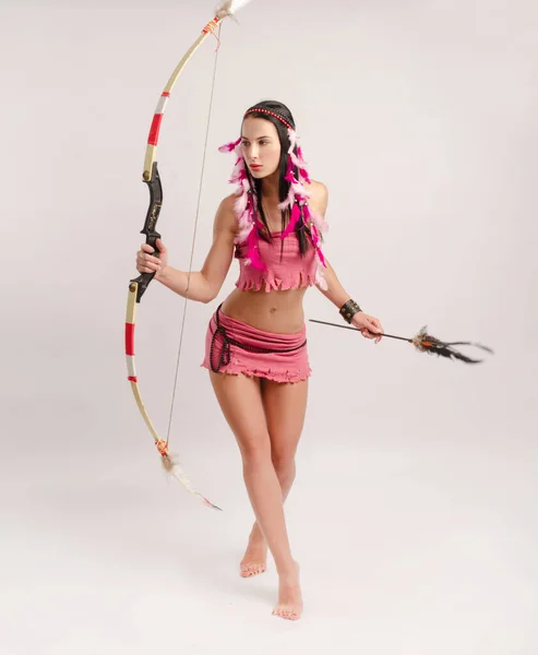 Slender girl in an Amazon costume with a bow and arrow in her hands — Stock Photo, Image