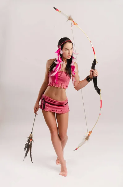 Smal flicka i en Amazon kostym med en båge och pil i händerna — Stockfoto