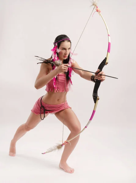 Slender girl in an Amazon costume with a bow and arrow in her hands — Stock Photo, Image