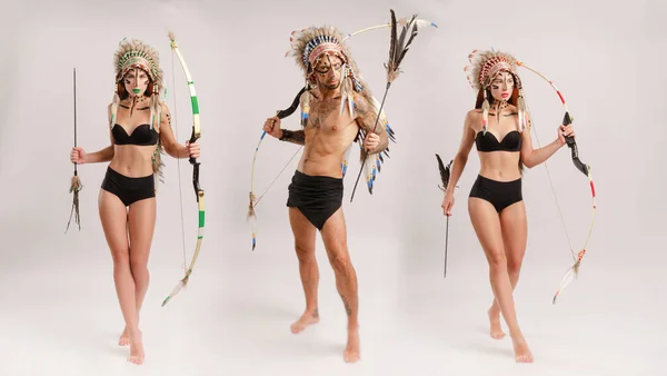 A man and woman in the image of indigenous peoples of America with a bow and arrow poses on a white background — Stock Photo, Image
