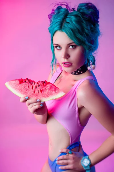 Ritratto di una donna luminosa con i capelli blu che mangia un'anguria in luce al neon — Foto Stock