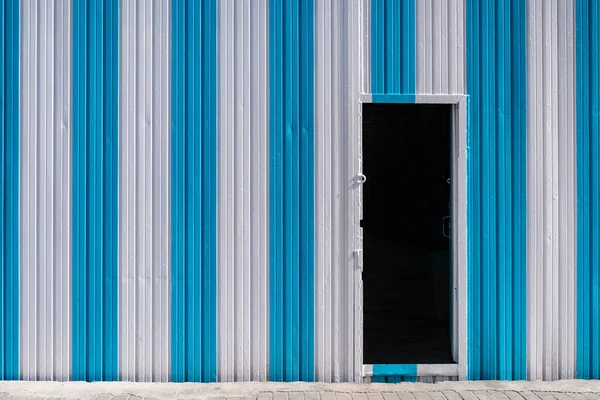 Μαύρη Πόρτα Στον Μπλε Και Άσπρο Ριγέ Μεταλλικό Τοίχο Βιομηχανικό — Φωτογραφία Αρχείου