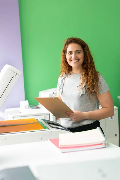 A young student at a copy center taking some copies for her final exams