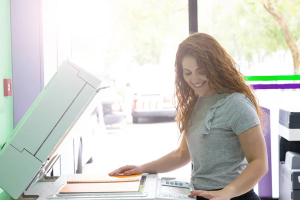 A young student at a copy center taking some copies for her final exams