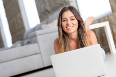 Güzel genç kadın evde dizüstü bilgisayarında rahatlatıcı