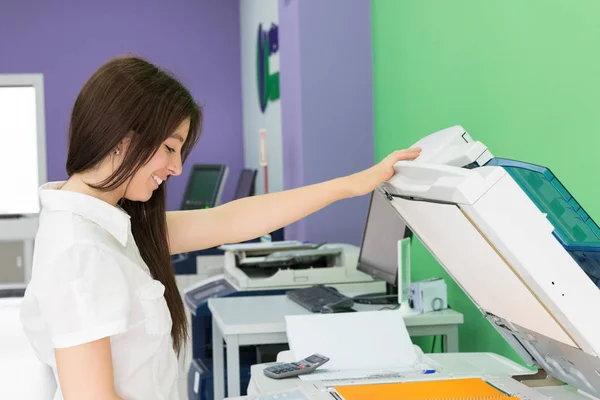 一个在复印中心的年轻学生为她的期末考试做了一些拷贝 — 图库照片