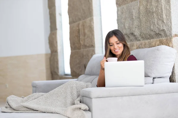 Güzel genç kadın evde dizüstü bilgisayarında rahatlatıcı