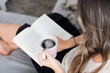  kadın evde kanepede rahatlatıcı ve kitap okuma