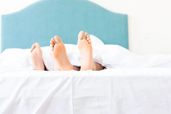 Feet of young couple relaxing in bed