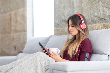 Güzel genç kadın bazı müzik dinlerken kanepede rahatlatıcı