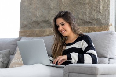 Güzel genç kadın evde dizüstü bilgisayarında rahatlatıcı