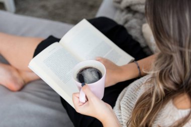 Güzel genç kadın evde rahatlatıcı bir kitap okuma