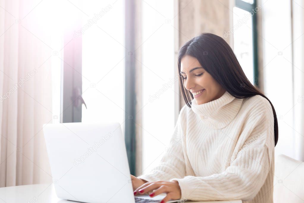 Beautiful young woman relaxing at home on her laptop computer
