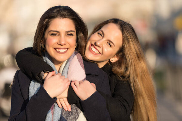 Young pretty girls best friends smiling and having fun, walking at the city. Shopping. Wearing stylish outerwear. Bright make up. Positive emotions. Outdoors lifestyle fashion close up portrait