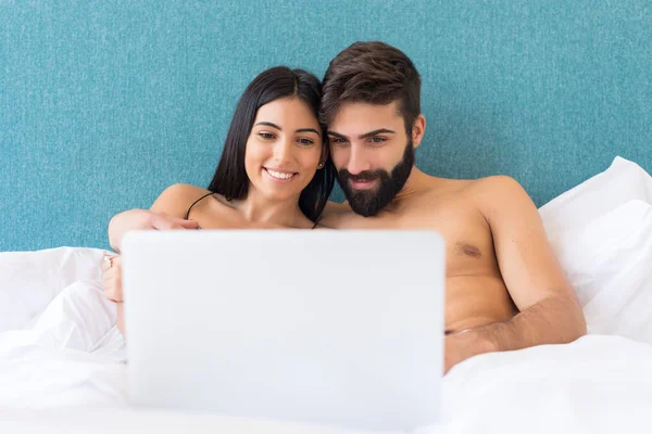 ベッドでリラックスしながら ノートパソコンの画面上で見て幸せなカップル — ストック写真