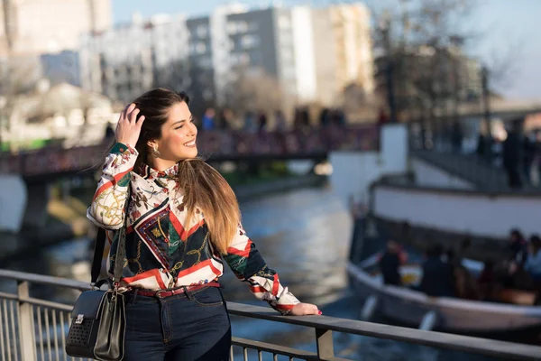 Kot pantolon ve gömlek güzel esmer genç kadın. Kentsel arka planda bahar moda fotoğraf.