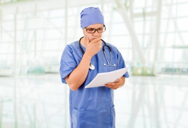 Erkek doktor, hastanede notlarıyla düşünüyor.