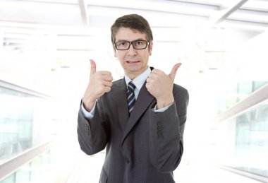 Genç iş adamı ofiste başparmağını kaldırıyor.