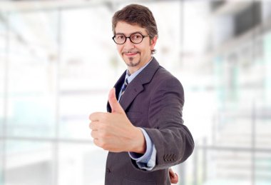 Genç iş adamı ofiste başparmağını kaldırıyor.