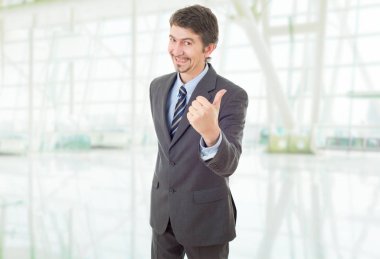 Mutlu iş adamı ofiste başparmağını kaldırıyor.