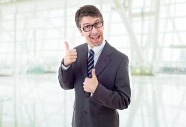 Genç iş adamı ofiste başparmağını kaldırıyor.