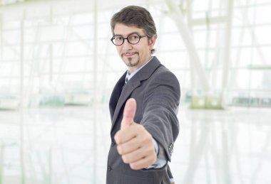 Genç iş adamı ofiste başparmağını kaldırıyor.