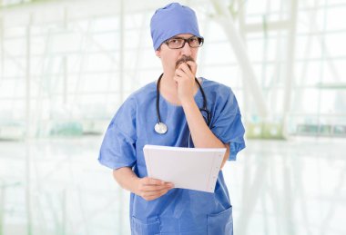 Erkek doktor hastanede düşünüyor.