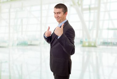 Mutlu iş adamı ofiste başparmağını kaldırıyor.