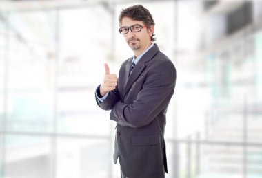 Genç iş adamı ofiste başparmağını kaldırıyor.