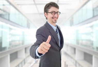 Genç iş adamı ofiste başparmağını kaldırıyor.
